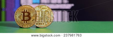 Two Gold Bitcoins Lie On The Green Surface On The Background Of The Display, Which Shows The Process