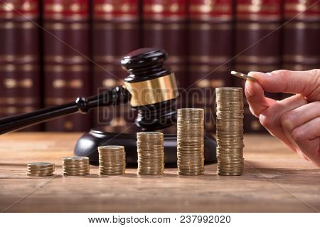 Close-up Of Human Hand Placing A Coin On Increasing Stacked Coins