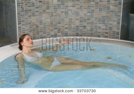 Belle jeune femme se détendre dans un bain à remous jacuzzi spa