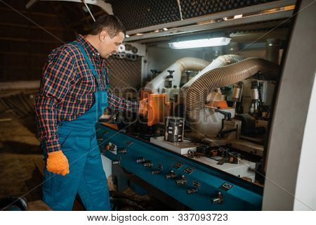 Carpenter in uniform near woodworking machine