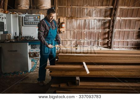 Carpenter with measuring tape measures boards