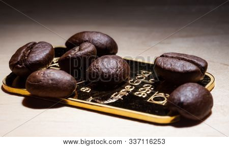 Several Roasted Coffee Beans On An Small Bar Of 999.9 Gold.
Selective Focus.