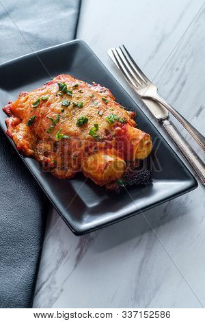 Italian American Baked Pasta Dish Stuffed Manicotti On Marble Kitchen Table