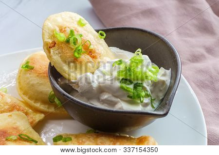 Delicious Authentic Polish Pierogies With Chopped Green Onion And Sour Cream