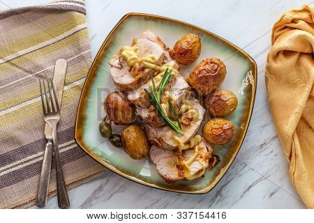 Sliced Honey Mustard Roast Pork Tenderloin With Baby Potatoes And Caperberry Garnish