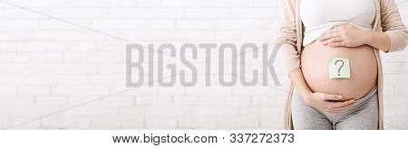 Pregnancy And Thinking Disorder. Pregnant Woman Belly With Question Mark, Panorama With Empty Space