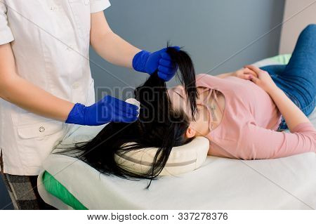 Young Woman Doctor Trichologist Examines The Hair Of A Pretty Girl Patient In His Office.
