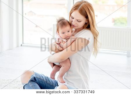 Happy mother kissing cute baby holding her up