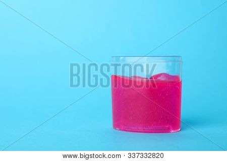 Pink Slime In Plastic Container On Light Blue Background. Space For Text