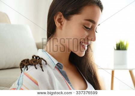 Young Woman With Striped Knee Tarantula On Shoulder At Home, Closeup