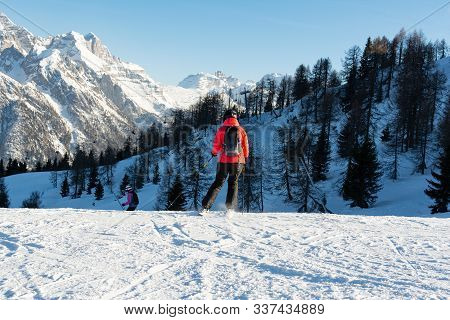 A Woman In A Red Jacket On Downhill Skiing At A Speed Down The Slope Against The Backdrop Of The Mou