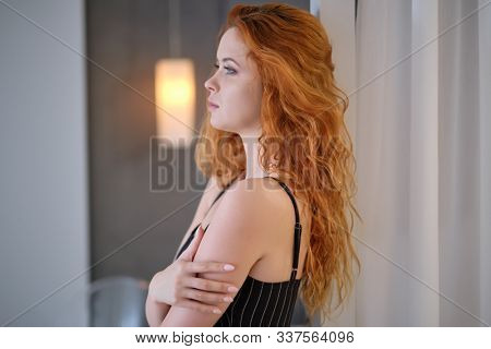Gorgeous young redhead woman with long coppery hair and blue eyes looking at the camera, close up head shot with copy space