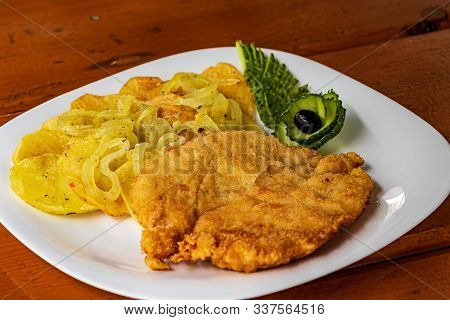 Home-style Fried Potatoes And A Large Piece Of Meat On A White Plate. Curly Chopped Green Cucumber. 