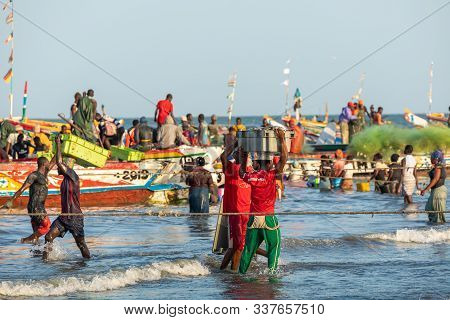 Tanji, The Gambia - November 21, 2019: Scene With Men And Women Carrying Fish From The Boats To The