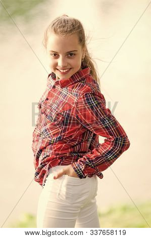 A Baby Girl. Adorable Baby With Long Blond Hair Smiling In Casual Plaid Style Outdoor. Happy Little 