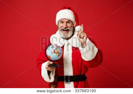 Cheerful Elderly Gray-haired Mustache Bearded Santa Man In Christmas Hat Posing Isolated On Red Back
