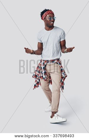 Full Length Of Playful Young African Man Dancing And Smiling While Standing Against Grey Background