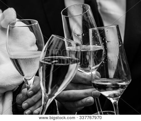 Clink The Glasses Of Sparkling Wine For Celebration On A Wedding In Black And White. Male And Female