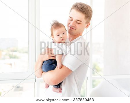 Father embracing infant near window