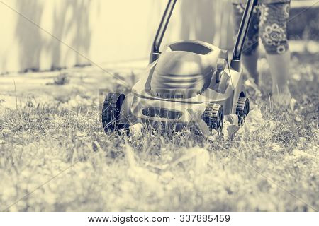 Deatil Of Plastic Toy Lwn Mower With Child Pushing It.