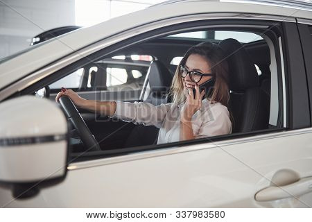 Some Good News. Beautiful Blonde Girl Sitting In The New Car With Modern Black Interior.