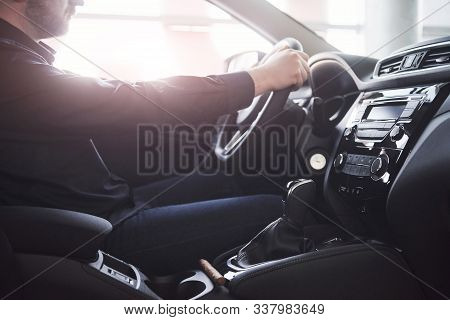 Gorgeous Sunlight. Close Up Side View Of Man Sitting In The Modern Car With Black Interior.
