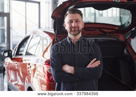 Having Good Mood. Front View Of Young Bearded Businessman Stands Near His Luxury Red Car.