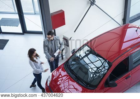 Top View Of Car Dealer Presenting New Car To The Customer.