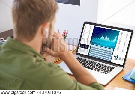 Caucasian businessman sitting at desk, using laptop with statistical data on screen. business communication and digital interface technology digital composite image.