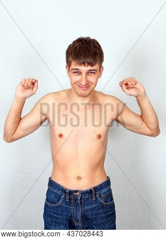 Skinny Young Man Muscle Flexing On The White Wall Background