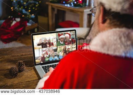 Caucasian santa claus on christmas laptop video call with diverse group of friends. christmas, festivity and communication technology.