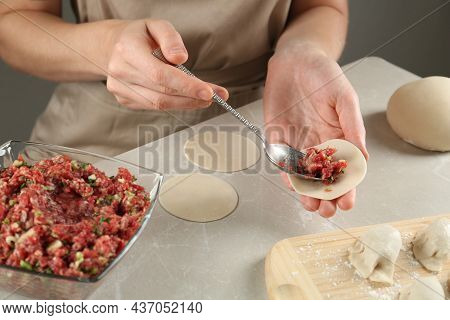 Woman Putting Gyoza Filling In Center Of Dough Wrapper At Light Table, Closeup