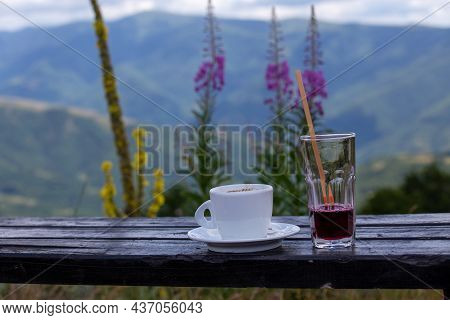 Close Up Of Coffee Cup And Glass Of Handmade Blueberry Juice On Wooden Table On Mountain Peak