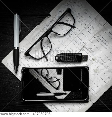 A Composition Of An Old Paper With Handwriting, Ballpoint Pen, Memory Stick, Glasses And Smartphone 