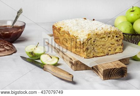 Apple And Coconut Oaf Cake On Wooden Cutting Board And Apples In A Vase