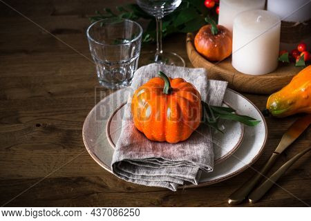 Autumn Table Setting With Plate, Pumpkin And Candles At Wooden Table. Thanksgiving Food Festive Dinn