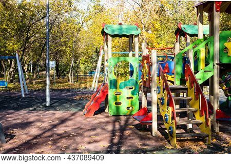 Colorful Wooden Slides And Houses On Playground In Public City Park On Sunny Autumn Day