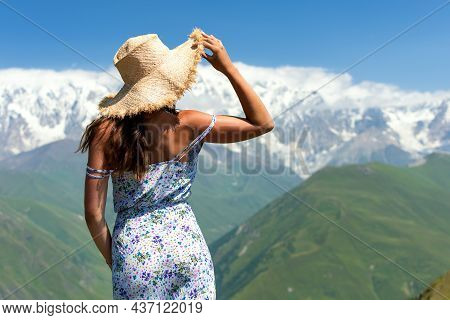 Young Beautiful Girl On The Edge Of A Cliff Looks At A Beautiful Mountain Landscape, Incredible View
