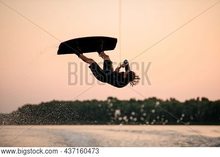 Male Wakeboarder Skilfully Jumping And Flips On Wakeboard Over Splashing Wave