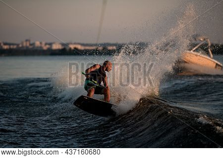 Active Athletic Man Trying To Stand On Splashing Wave On A Wakeboard