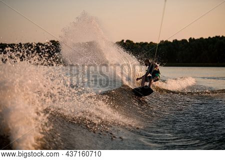 Active Man Energetically Balancing On Great Splasing Wave On Wakesboard.