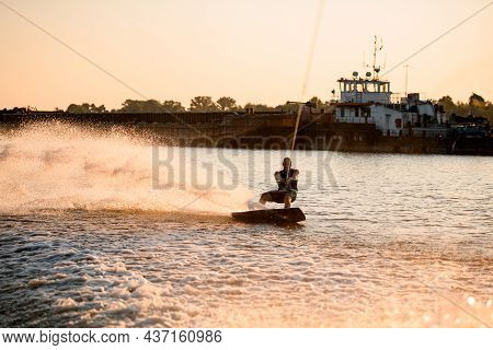 Active Man Wakeboarder Riding Water And A Lot Of Splashes Behind Him