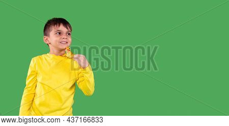Photo Of A Smiling School Aged Boy In Yellow Hoodie Looking Aside And Holding The Dinosaur Toy On Hi