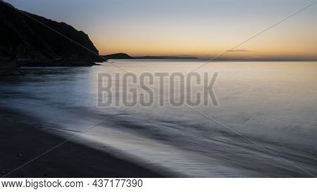 Beautiful Sunrise Over Pentewan Sands In Cornwall With Pastel Sky And Long Exposure Ocean