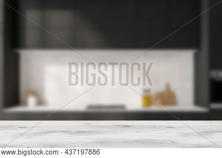 Light Wood Table On Blurred Background Of Modern Black Kitchen With White Splashback. Concept Of Pro