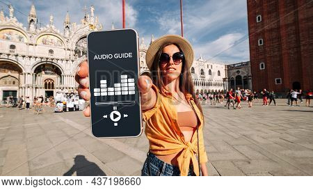 Audio Guide Online App On Digital Mobile Smartphone. Happy Young Student Woman Holding Phone Listeni