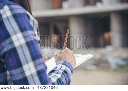 Woman Construction Engineer Writing Note Wear Plaid Shirt Safety White Hard Hat At Construction Site