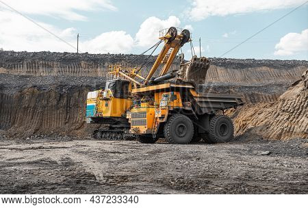 Large Quarry Dump Truck. Big Yellow Mining Truck At Work Site. Loading Coal Into Body Truck. Product