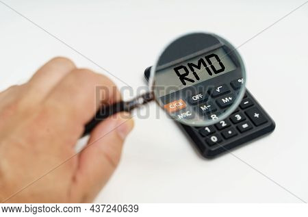 Business And Finance Concept. A Man Looks Through A Magnifying Glass At A Calculator On The Screen O