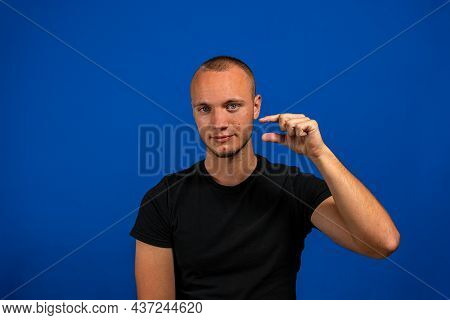 Young Handsome Man Show A Little Bit. Gesture. On A Blue Background